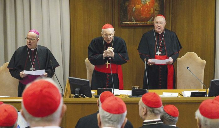 Cardinal Giovanni Battista Re, dean of the College of Cardinals, centre, leads cardinals in prayer during their first general congregation April 22, 2025, in the Vatican Synod Hall. To Cardinal Re’s left is US Cardinal Kevin J. Farrell, chamberlain of the Holy Roman Church, and to the left is Archbishop Ilson Montanari, secretary of the College of Cardinals. (CNS photo/Vatican Media)
