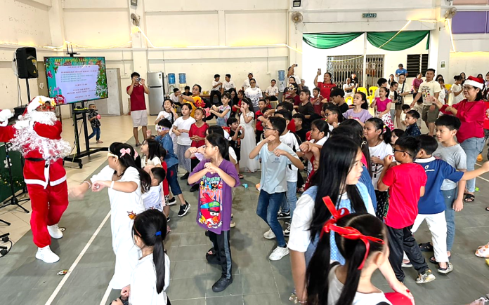 Children being entertained by a skinny Santa Claus.